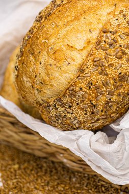 Beyaz zemin üzerinde susamlı ve ayçiçeği tohumlu tam bir buğday ekmeği.