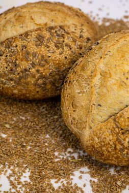 Beyaz zemin üzerinde susamlı ve ayçiçeği tohumlu tam bir buğday ekmeği.