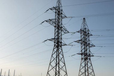 Sahada yüksek voltajlı elektrik hattı var. Akşamları elektrik direkleri. Elektrik kulesi. Güç iletim hatları. Enerji güvenliği ve temiz enerji.  