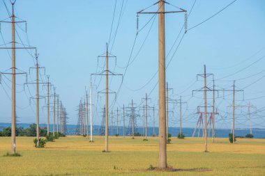 Sahada yüksek voltajlı elektrik hattı var. Akşamları elektrik direkleri. Elektrik kulesi. Güç iletim hatları. Enerji güvenliği ve temiz enerji.  