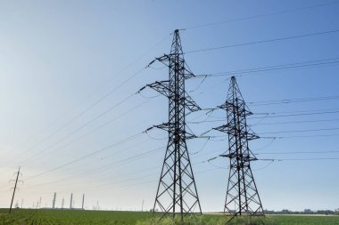 Mavi gökyüzüne karşı yüksek voltajlı elektrik hatları ve kolonlar. Elektrik kulesi. Güç iletim hatları. Enerji güvenliği ve temiz enerji.  