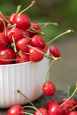 Bahçedeki bir kasede ağaçtan taze koparılmış kırmızı kirazlar.