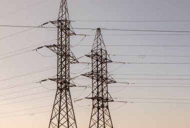 Mavi gökyüzüne karşı yüksek voltajlı elektrik hatları ve kolonlar. Elektrik kulesi. Güç iletim hatları. Enerji güvenliği ve temiz enerji.  