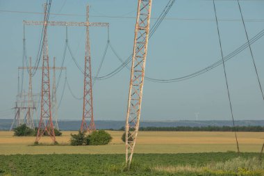 Mavi gökyüzüne karşı yüksek voltajlı elektrik hatları ve kolonlar. Elektrik kulesi. Güç iletim hatları. Enerji güvenliği ve temiz enerji.  