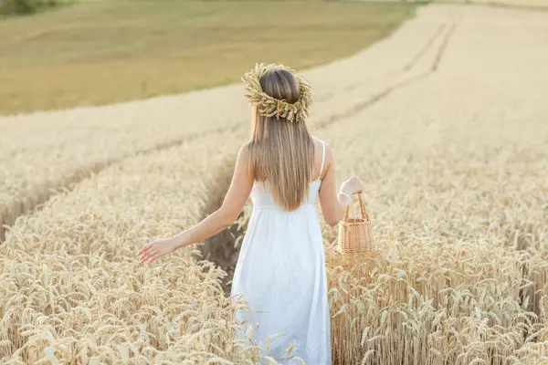 Beyaz elbiseli güzel bir kadının portresi ve tarlada buğday kulaklı bir çelenk.