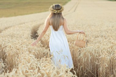 Buğday tarlasında sepeti olan güzel bir genç kadının portresi.