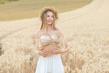 Buğday tarlasında sepeti olan güzel bir genç kadının portresi.