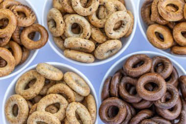 Koyu arkaplanda yeni pişmiş mini simit. Üst Manzara. Yüzük şeklinde krakerler, yakın plan. Küçük ekmek çemberi bisküvisi. Farklı simit türleri olan kaseler..