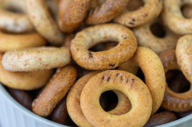 Koyu arkaplanda yeni pişmiş mini simit. Üst Manzara. Yüzük şeklinde krakerler, yakın plan. Küçük ekmek çemberi bisküvisi. Farklı simit türleri olan kaseler..