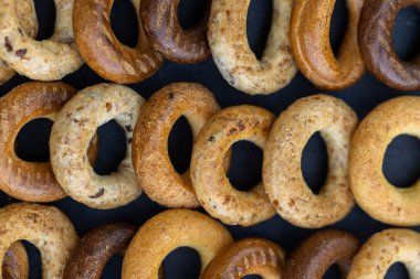 Koyu arkaplanda yeni pişmiş mini simit. Üst Manzara. Yüzük şeklinde krakerler, yakın plan. Küçük ekmek çemberi bisküvisi. Farklı simit türleri olan kaseler..