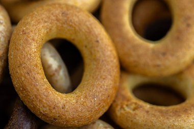 Koyu arkaplanda yeni pişmiş mini simit. Üst Manzara. Yüzük şeklinde krakerler, yakın plan. Küçük ekmek çemberi bisküvisi. Farklı simit türleri olan kaseler..