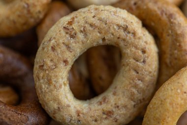 Koyu arkaplanda yeni pişmiş mini simit. Üst Manzara. Yüzük şeklinde krakerler, yakın plan. Küçük ekmek çemberi bisküvisi. Farklı simit türleri olan kaseler..