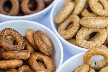 Koyu arkaplanda yeni pişmiş mini simit. Üst Manzara. Yüzük şeklinde krakerler, yakın plan. Küçük ekmek çemberi bisküvisi. Farklı simit türleri olan kaseler..