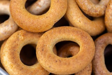 Koyu arkaplanda yeni pişmiş mini simit. Üst Manzara. Yüzük şeklinde krakerler, yakın plan. Küçük ekmek çemberi bisküvisi. Farklı simit türleri olan kaseler..