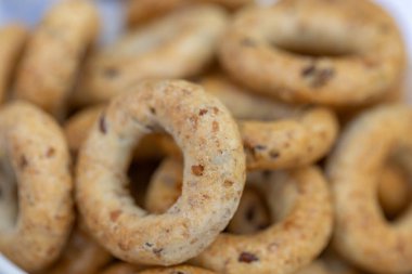 Koyu arkaplanda yeni pişmiş mini simit. Üst Manzara. Yüzük şeklinde krakerler, yakın plan. Küçük ekmek çemberi bisküvisi. Farklı simit türleri olan kaseler..