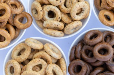 Koyu arkaplanda yeni pişmiş mini simit. Üst Manzara. Yüzük şeklinde krakerler, yakın plan. Küçük ekmek çemberi bisküvisi. Farklı simit türleri olan kaseler..