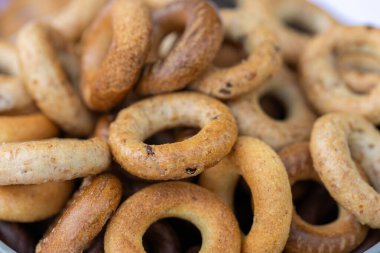 Koyu arkaplanda yeni pişmiş mini simit. Üst Manzara. Yüzük şeklinde krakerler, yakın plan. Küçük ekmek çemberi bisküvisi. Farklı simit türleri olan kaseler..