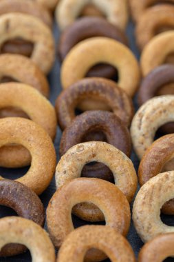 Koyu arkaplanda yeni pişmiş mini simit. Üst Manzara. Yüzük şeklinde krakerler, yakın plan. Küçük ekmek çemberi bisküvisi. Farklı simit türleri olan kaseler..
