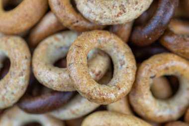 Koyu arkaplanda yeni pişmiş mini simit. Üst Manzara. Yüzük şeklinde krakerler, yakın plan. Küçük ekmek çemberi bisküvisi. Farklı simit türleri olan kaseler..