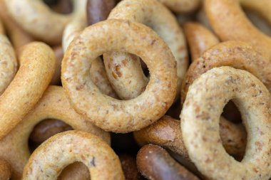 Koyu arkaplanda yeni pişmiş mini simit. Üst Manzara. Yüzük şeklinde krakerler, yakın plan. Küçük ekmek çemberi bisküvisi. Farklı simit türleri olan kaseler..