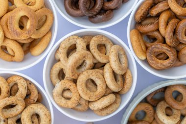 Koyu arkaplanda yeni pişmiş mini simit. Üst Manzara. Yüzük şeklinde krakerler, yakın plan. Küçük ekmek çemberi bisküvisi. Farklı simit türleri olan kaseler..