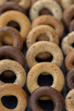 Koyu arkaplanda yeni pişmiş mini simit. Üst Manzara. Yüzük şeklinde krakerler, yakın plan. Küçük ekmek çemberi bisküvisi. Farklı simit türleri olan kaseler..