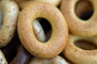 Koyu arkaplanda yeni pişmiş mini simit. Üst Manzara. Yüzük şeklinde krakerler, yakın plan. Küçük ekmek çemberi bisküvisi. Farklı simit türleri olan kaseler..