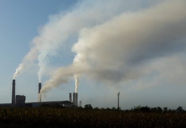 Fabrika bacalarından mavi gökyüzüne doğru yükselen endüstriyel kirlilik. Ekolojik felaket. Fabrika bacaları dumanla dolu.
