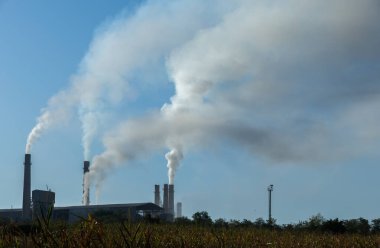 Fabrika bacalarından mavi gökyüzüne doğru yükselen endüstriyel kirlilik. Ekolojik felaket. Fabrika bacaları dumanla dolu.