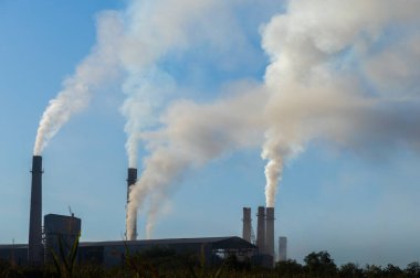 Fabrika bacalarından mavi gökyüzüne doğru yükselen endüstriyel kirlilik. Ekolojik felaket. Fabrika bacaları dumanla dolu.