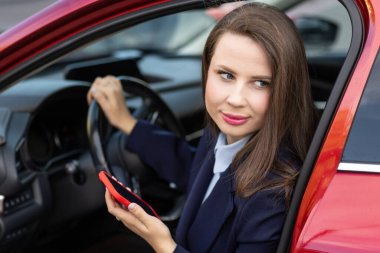 Gündelik kıyafet içinde çekici genç bir kadın sürücü, sürücü arabası, yol güvenliği ve ulaşım teması. Araba kullanan genç bir kadın. Seyahat kavramı.