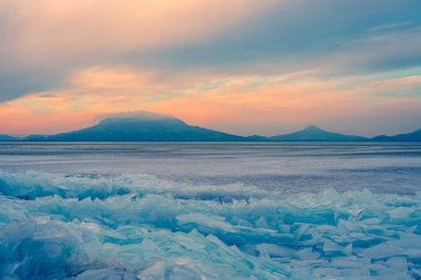 Fonyod, Macaristan - Donmuş Balaton sahilinde güzel buzdağları. Badacsony ve Gulacs arka planda muhteşem bulutlu bir günbatımı ile.