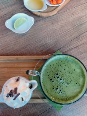 Tahta bir tabakta, cam bir fincanda, organik kibrit yeşil çay..