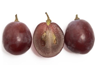 Yakın plan dilimlenmiş ve iki taze organik kırmızı üzüm. Lezzetli meyve. Beyaz arka planda izole edilmiş bir dalı var.