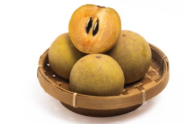 Yarısı kesilmiş bir grup ve taze organik sapodilla. Beyaz arka planda izole edilmiş bambu bir sepet içinde lezzetli meyveler.