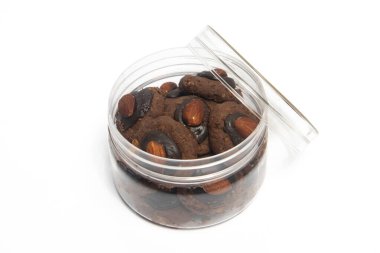 Çikolata ve mısır gevreğinden yapılmış Afgan kurabiyeleri. Beyaz arka planda izole edilmiş bir kavanozun içinde badem var.