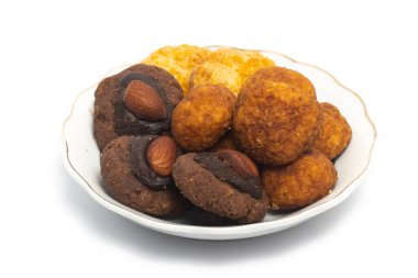 Beyaz arka planda izole edilmiş küçük beyaz bir tabakta çeşitli palmiye peyniri, mısır gevreği ve Afgan kurabiyeleri.