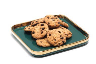 Beyaz arka planda izole edilmiş yeşil bir tabakta çikolatalı kurabiye grubu.