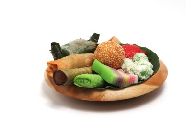 Various kinds of Jajan Pasar, traditional Indonesian market snacks, on the wooden plate with banana leaves isolated on white background clipping path clipart