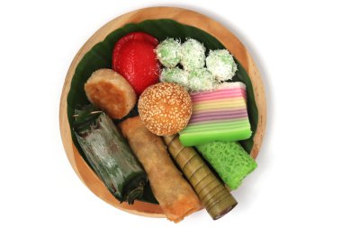 Various kinds of Jajan Pasar, traditional Indonesian market snacks, on the wooden plate with banana leaves top view isolated on white background clipping path clipart