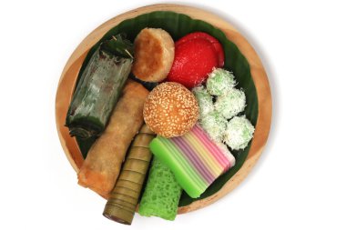 Various kinds of Jajan Pasar, traditional Indonesian market snacks, on the wooden plate with banana leaves isolated on white background clipping path clipart