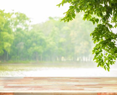 Abstract Natural wood table with Morning sun light with wind blowing leaves in the lake park. : Top view of plank wood for graphic stand product, interior design or montage display your product