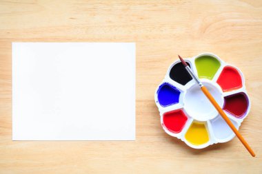 Boya fırçalarının üst görüntüsü palet ve beyaz kağıtlı suluboya boyalar. Kopyalama alanı olan resim ve metin iletisi ekle..