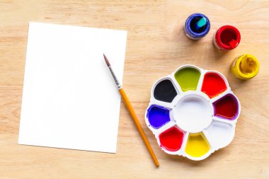 Boya fırçalarının üst görüntüsü palet ve beyaz kağıtlı suluboya boyalar. Kopyalama alanı olan resim ve metin iletisi ekle..