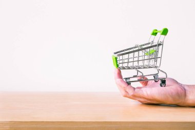 Shopping cart on man hand with wood table. E-commerce and global network online business. copy space for art work design or add text message. Online shopping