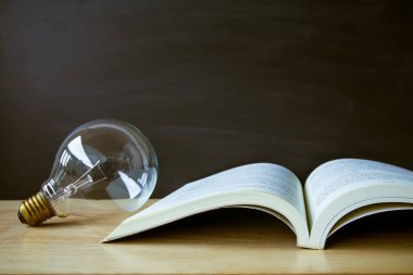 Back to school concept. Open book on table with blackboard backdrop copy space for art work design or add text message.