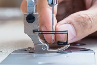 Sewing machine and thread rolling. Man hand work needles thread