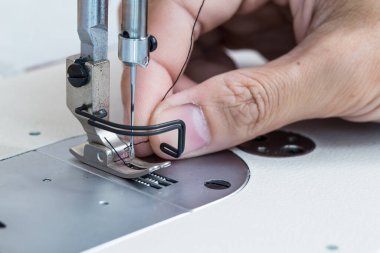 Sewing machine and thread rolling. Man hand work needles thread