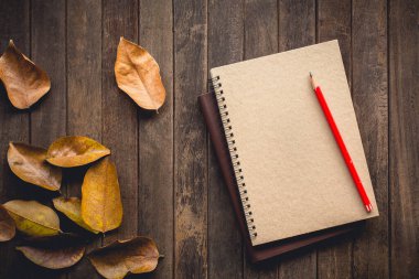 Vintage picture tone of Autumn background. The fallen autumn leaves and notebook on wooden garden table. can used add text message or greeting card.