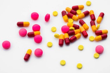 Beyaz arka planda çeşitli ilaç ve renk kapsülleri var. Metin iletisi eklemek için boşluk kopyala.